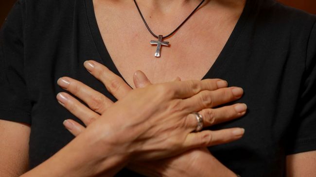 Betende Frau mit überkreuzten Händen über dem Herzen