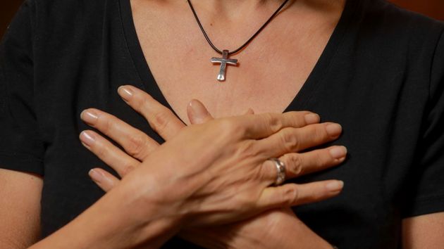 Betende Frau mit überkreuzten Händen über dem Herzen